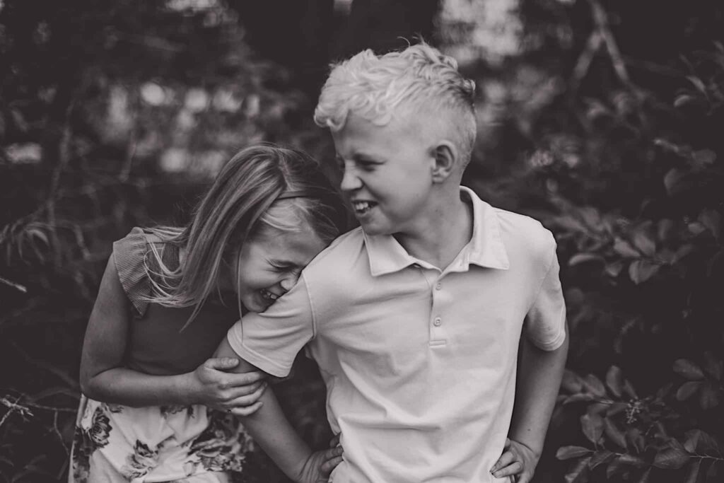 A photograph of siblings laughing together in black and white
